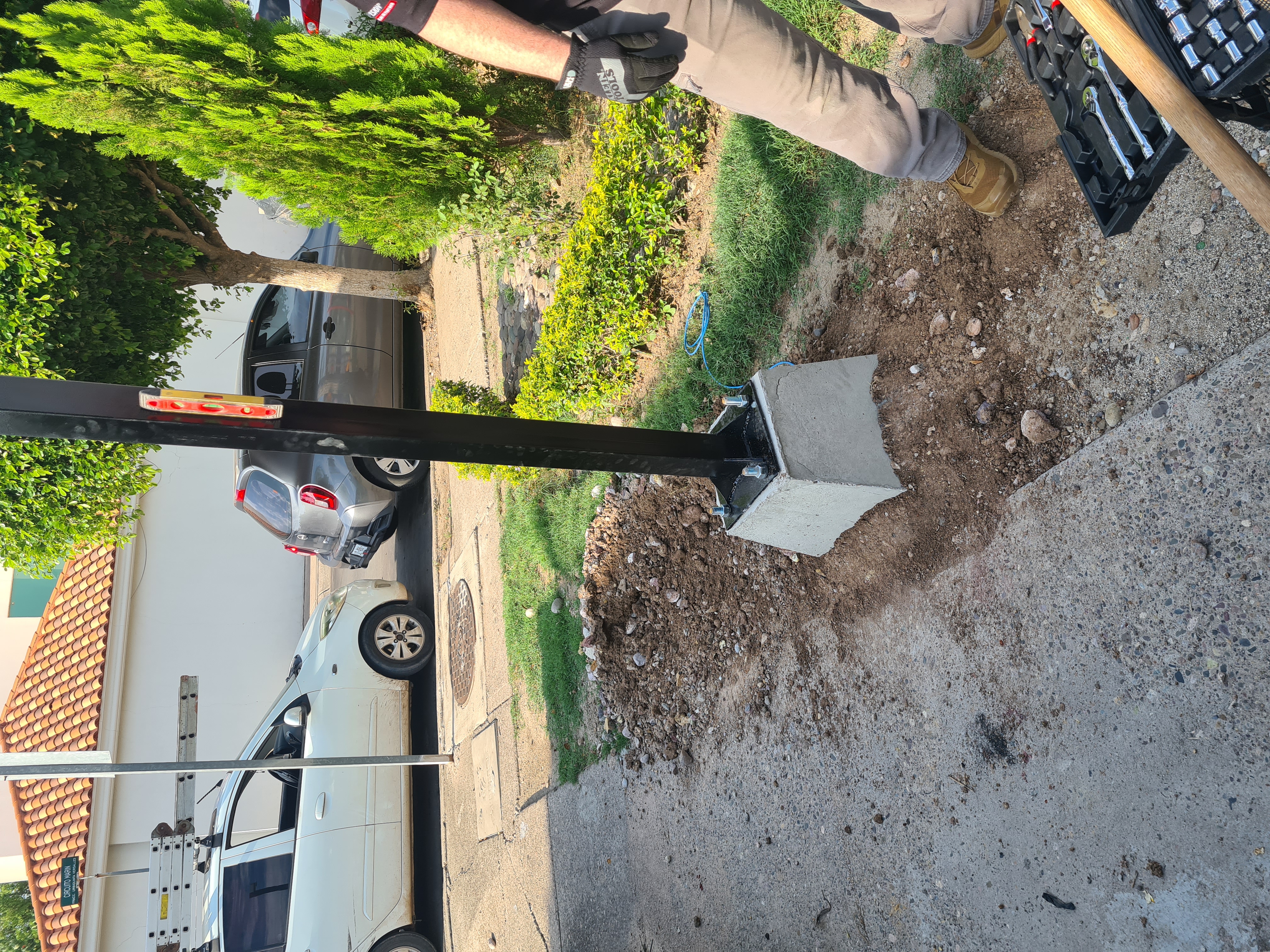 Técnico nivelando poste recién instalado sobre base de concreto